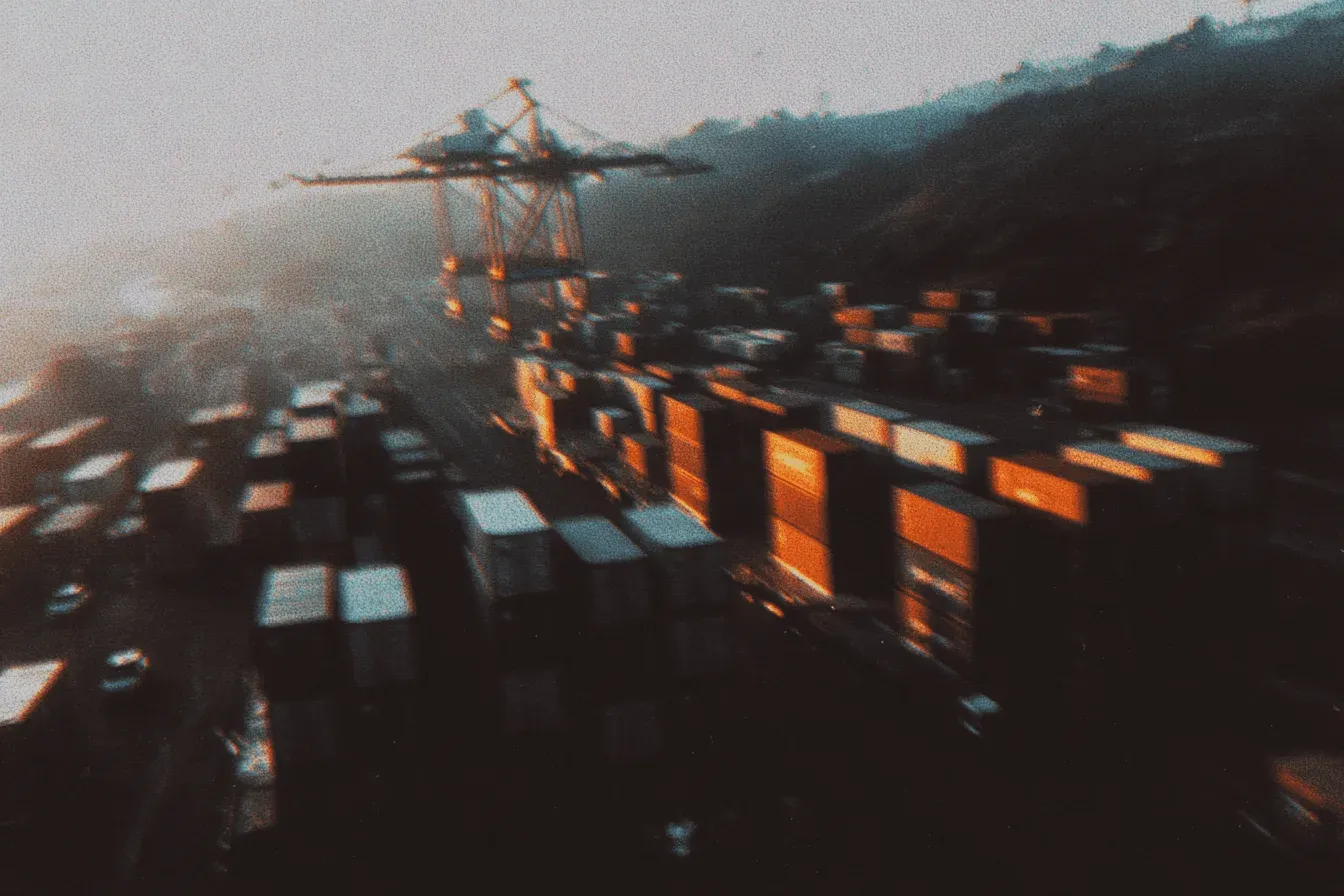 A container yard at sunset with a crane in the haze