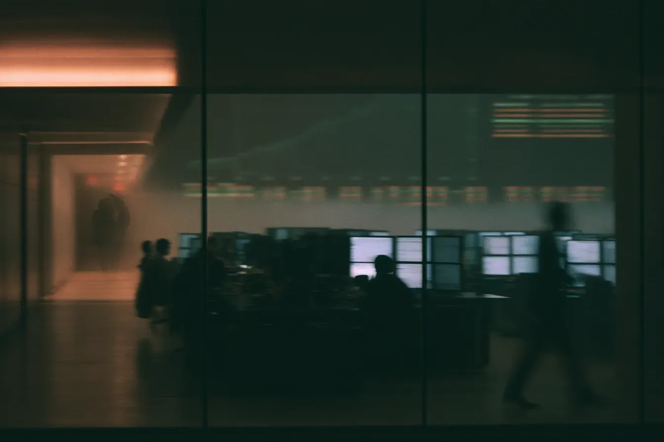 A trading floor in the evening, seen through a glass partition