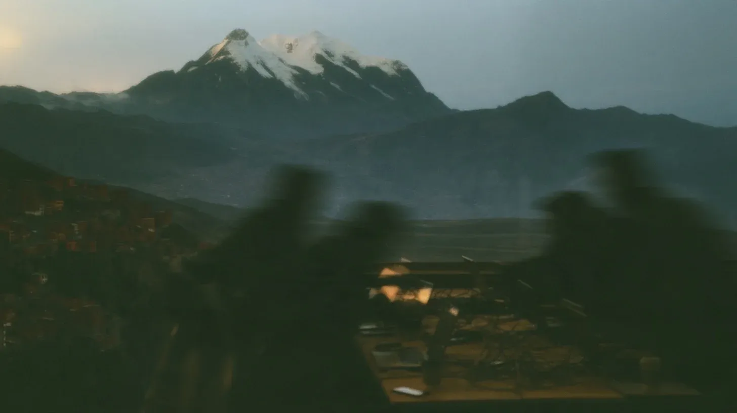 Developers working on laptops at a long table, with La Paz hillside houses and Mount Illimani in the background