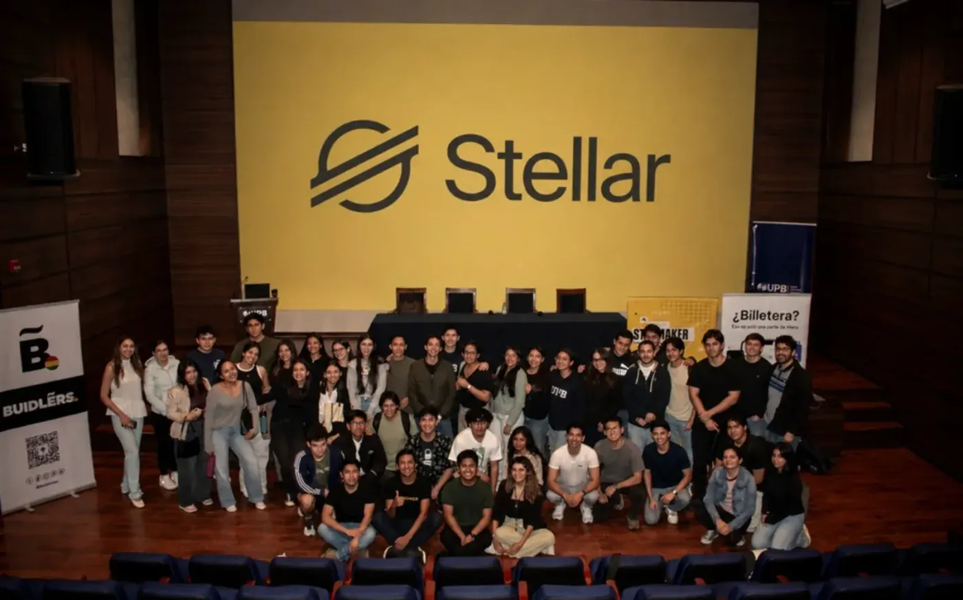 Students gathered on stage at UPB in Santa Cruz in front of a large Stellar logo, with Buidlers Bolivia and UPB banners